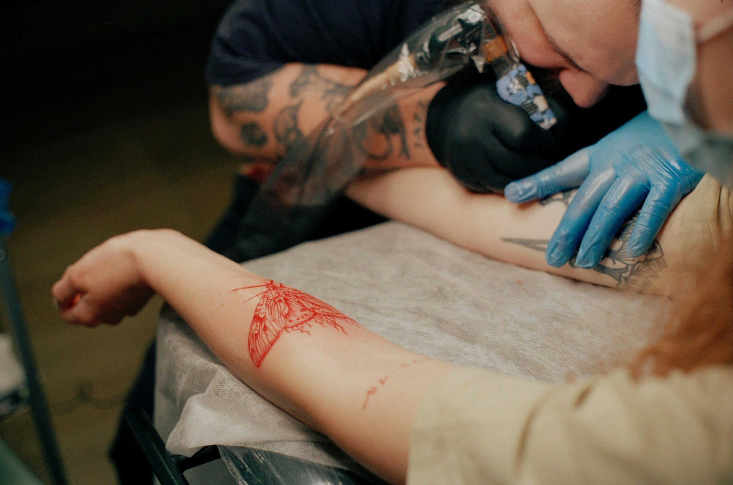 Detailed view of a tattoo artist tattooing a client's arm in a studio.